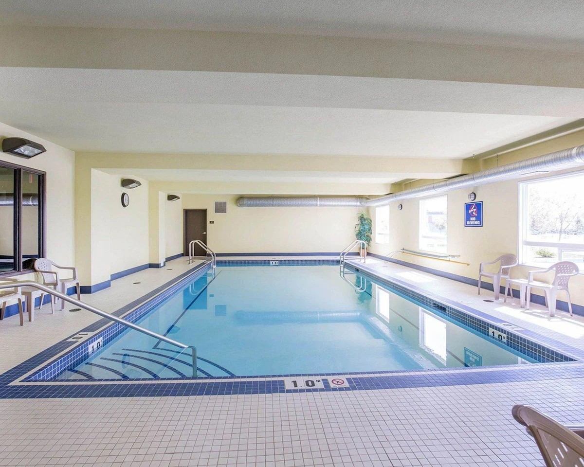 Indoor swimming pool at Comfort Inn & Suites with handrails, seating, and natural light.