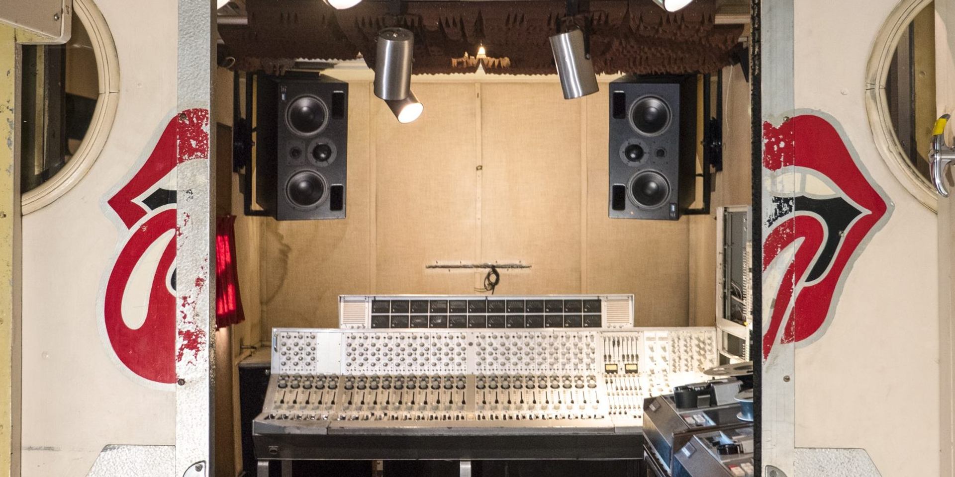 Vintage recording studio control room with large mixing console and speakers, lips logo on doors.