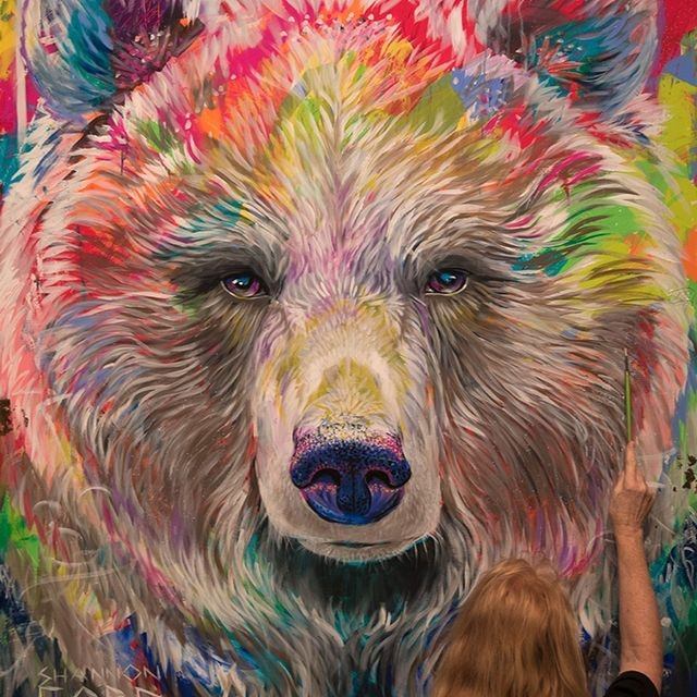 Person paints colourful bear portrait on large canvas.