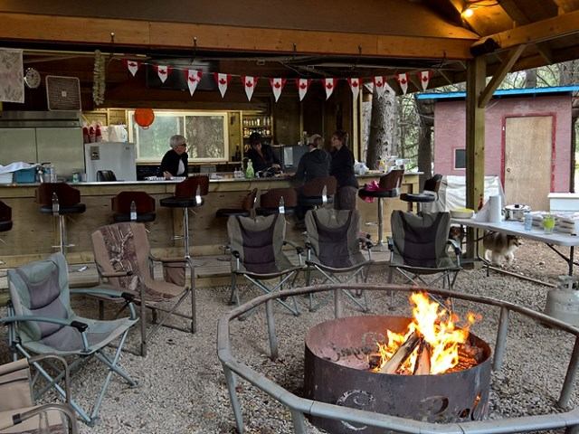 Rustic River Resort outdoor camp kitchen with fire pit and camping chairs.