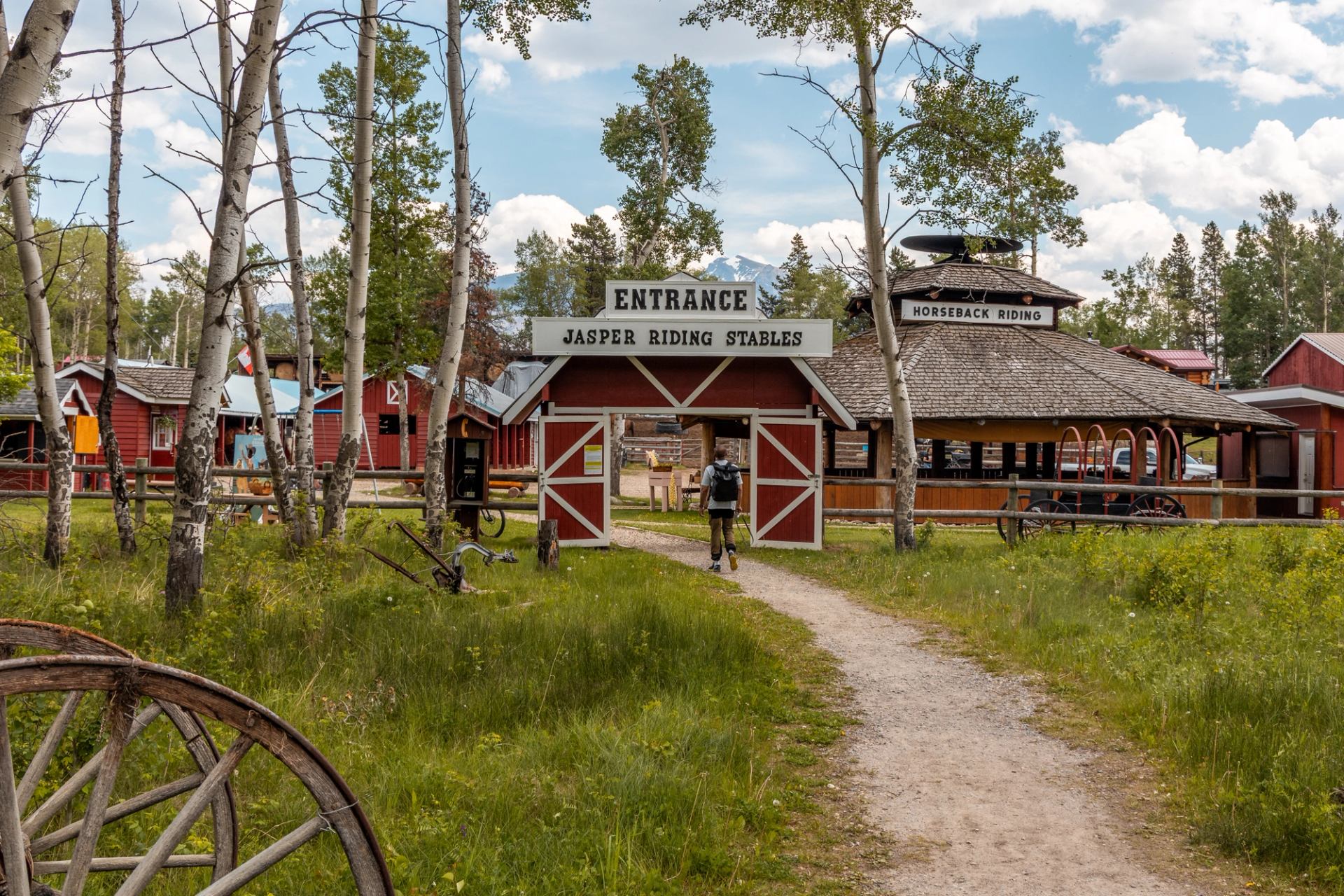 Entrance to Jasper Riding Stables with rustic gate and red buildings.