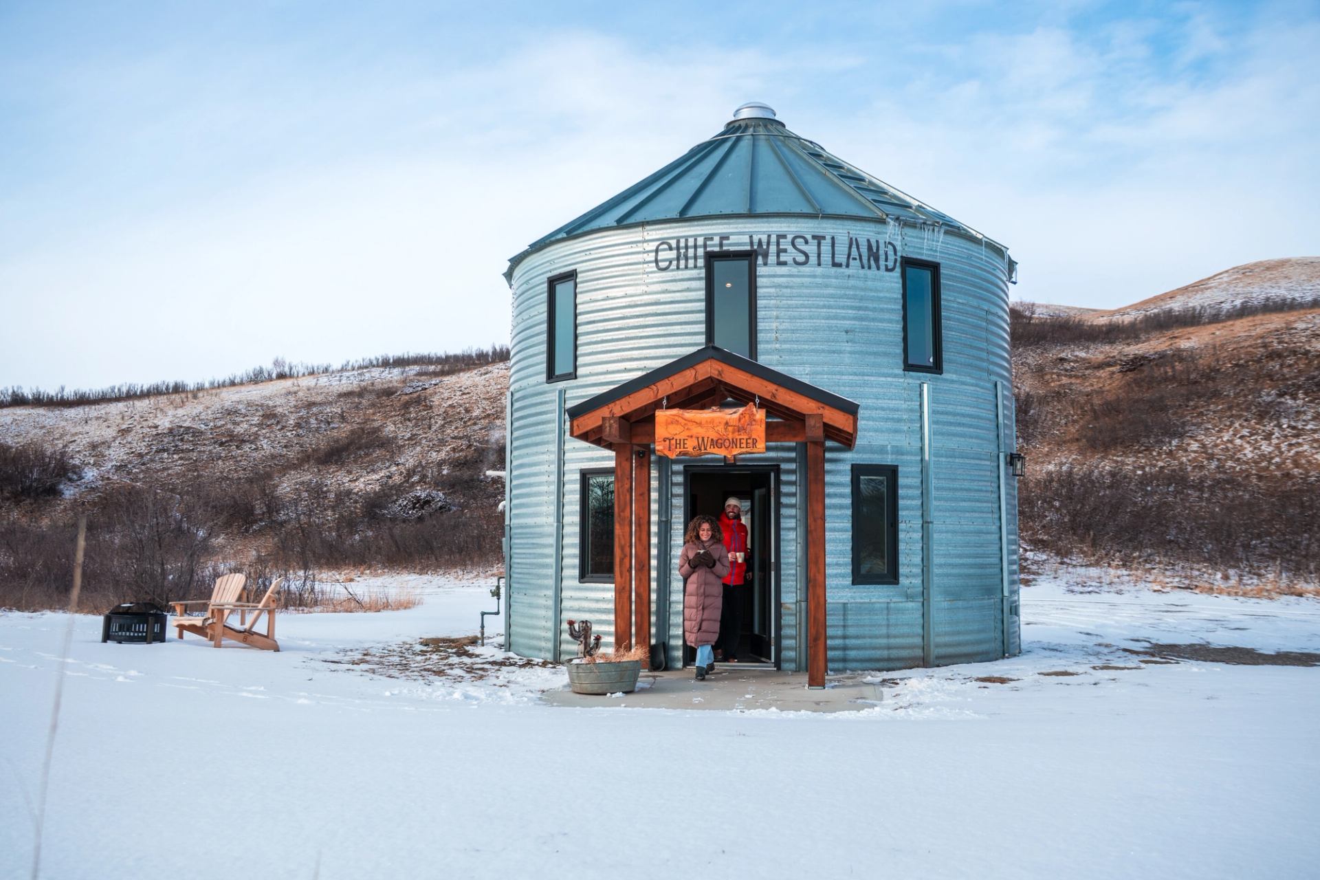 Two people stand at The Wagoneer entrance beneath Chief Westland signage in snow.
