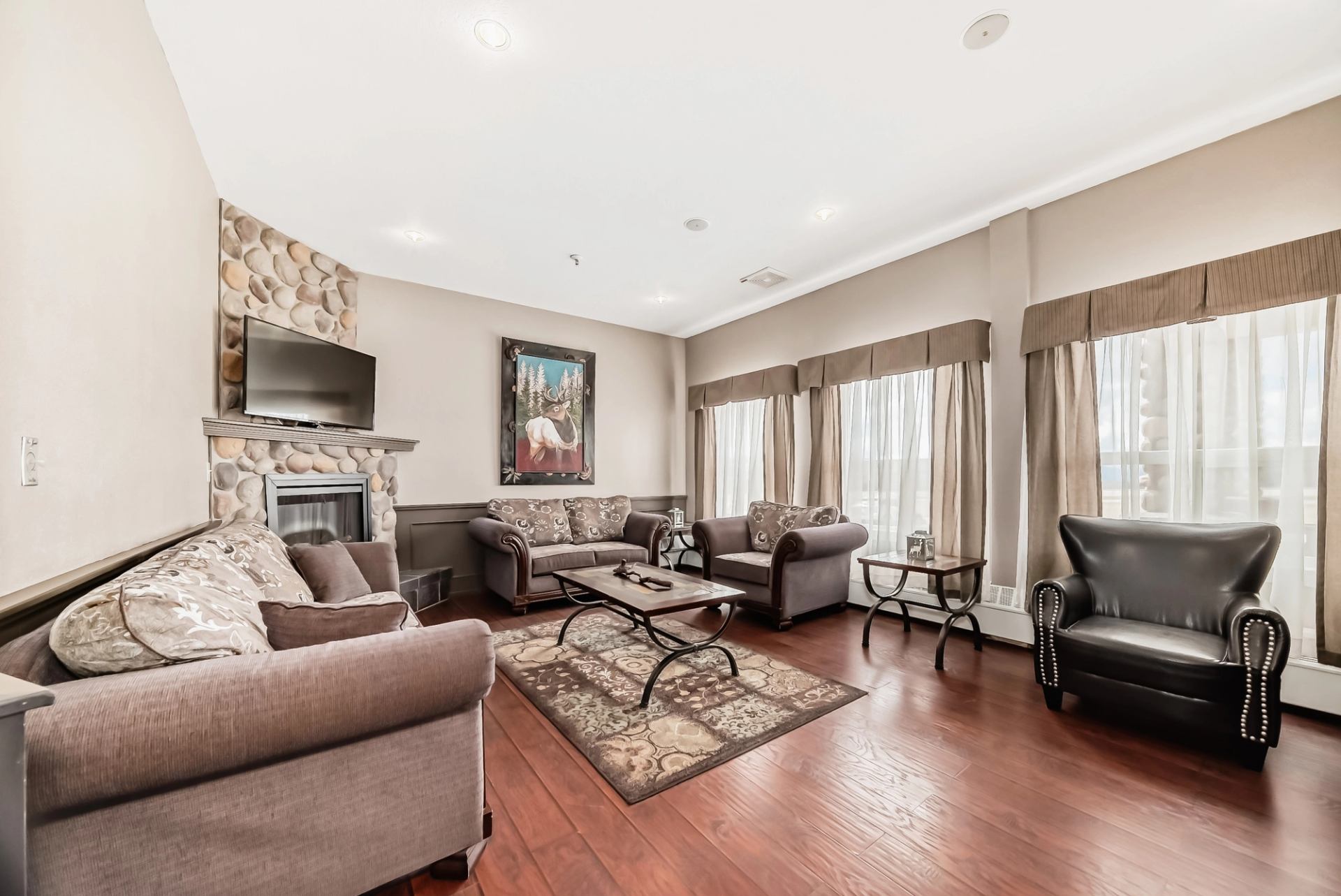 Cozy lounge with sofas, armchair, coffee table, and fireplace with TV at Grande Cache Inn.