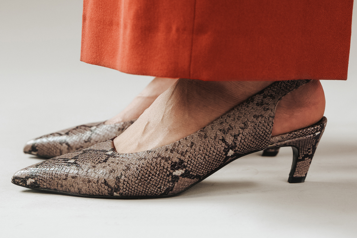 Snakeskin pointed-toe shoes with open back, worn with cropped orange pants.