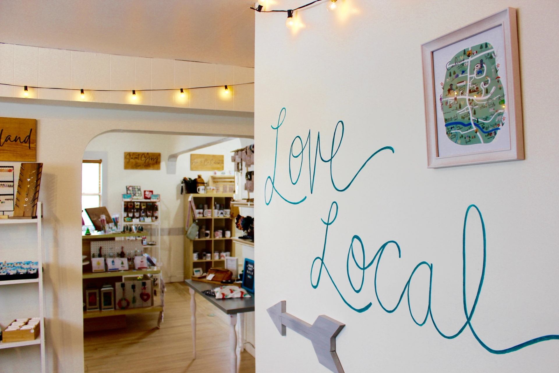The store interior, with warm white string lights, wooden floors, and Love Local written on the wall
