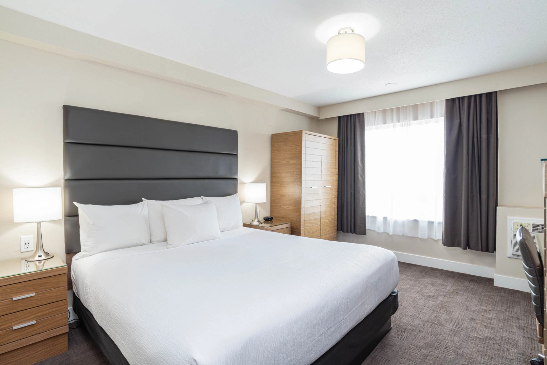 Hotel bedroom with large bed, bedside tables, wardrobe and window with curtains.