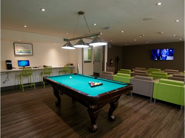 Modern rec room with pool table, lounge chairs, and computer desk.