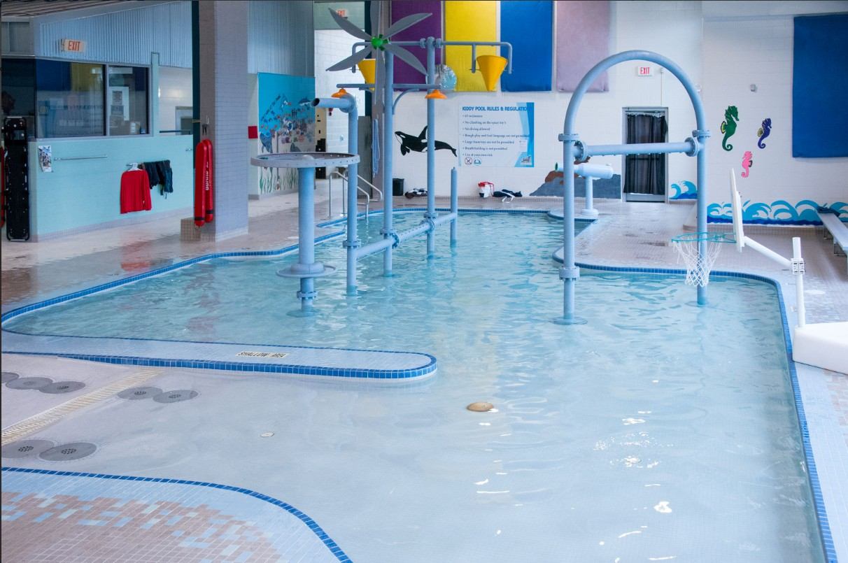 Shallow pool with water play structures, buckets, and colorful features