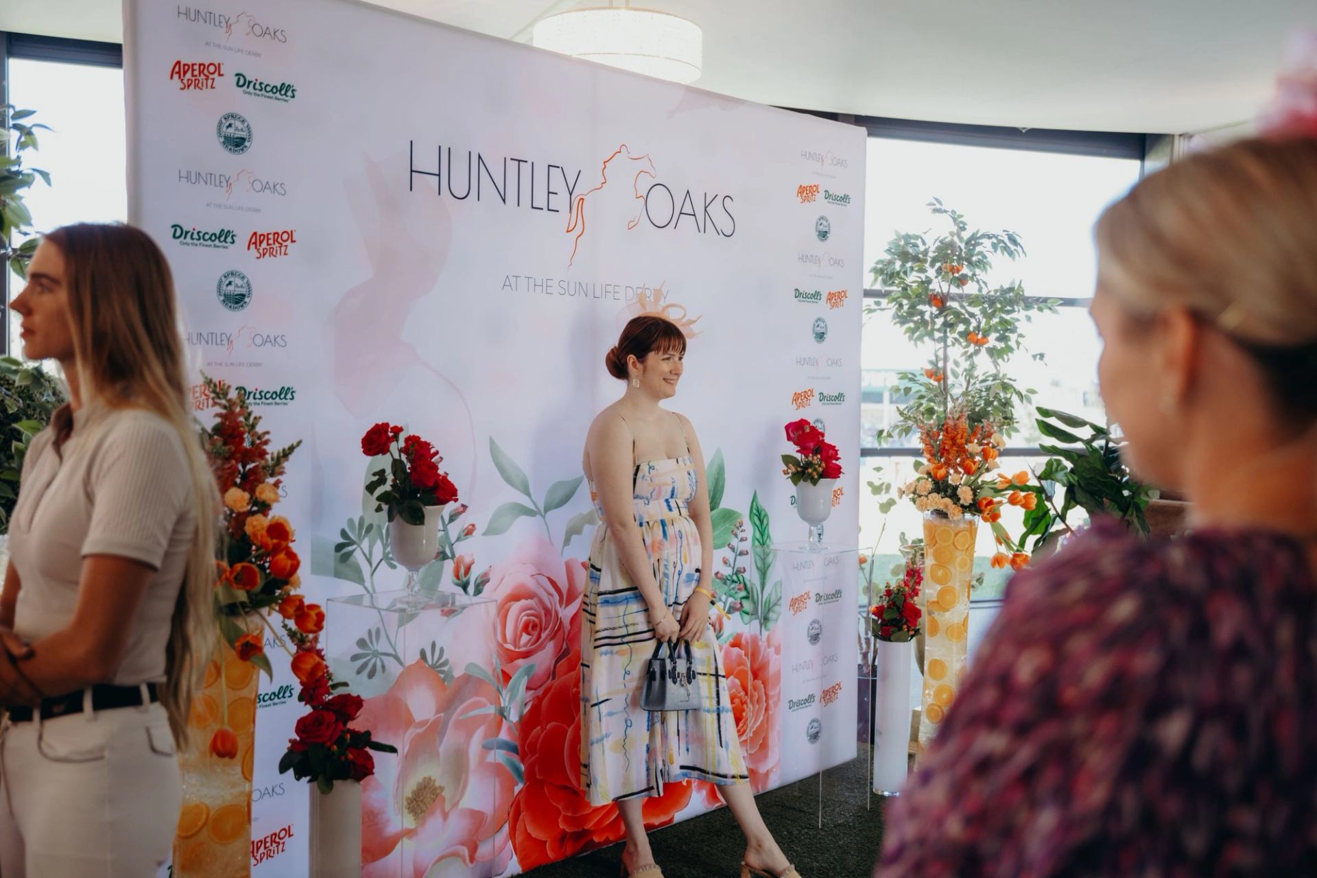 Huntley Oaks at the Sun Life Derby banner with flowers and event attendees.
