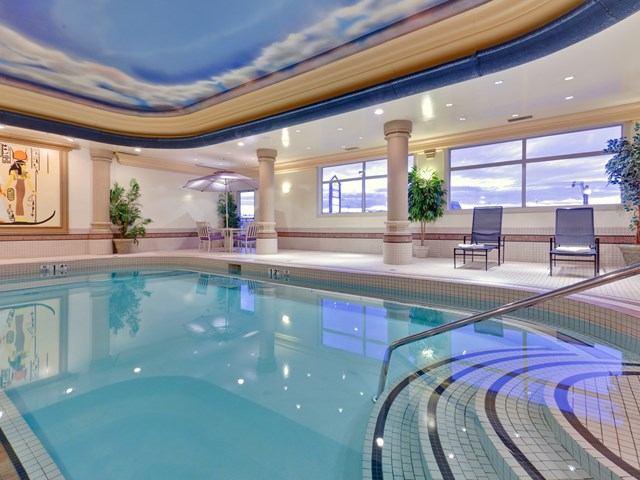 Elegant indoor pool with sky ceiling and lounge chairs.