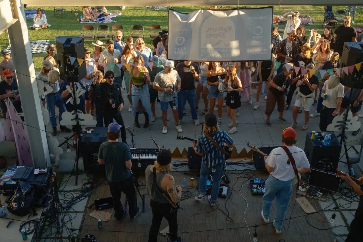 Outdoor music stage with crowd watching musicians with guitars and microphones at a festival.