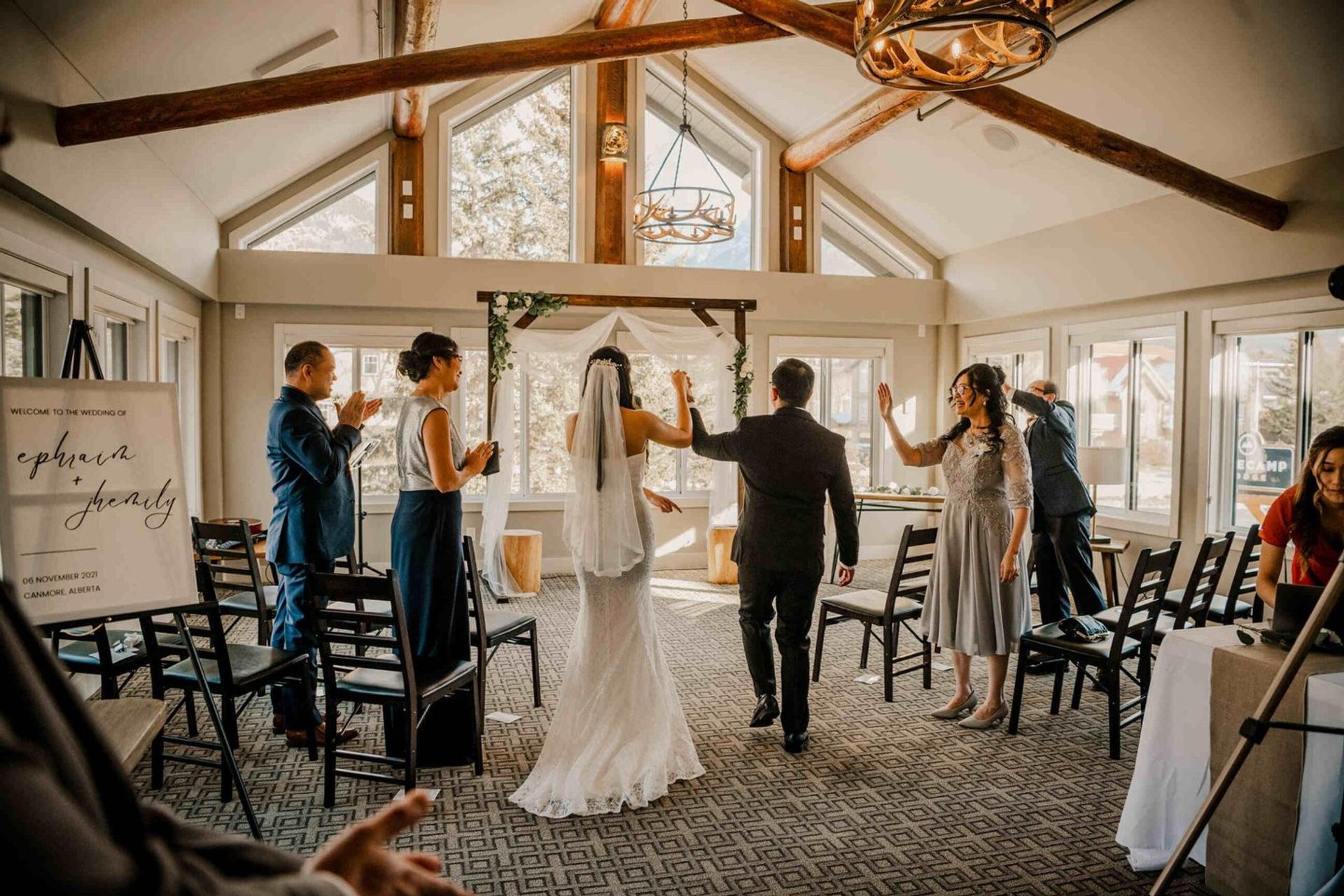 Indoor wedding ceremony at Basecamp Lodge with wooden beams, bright windows, and a decorated arch.