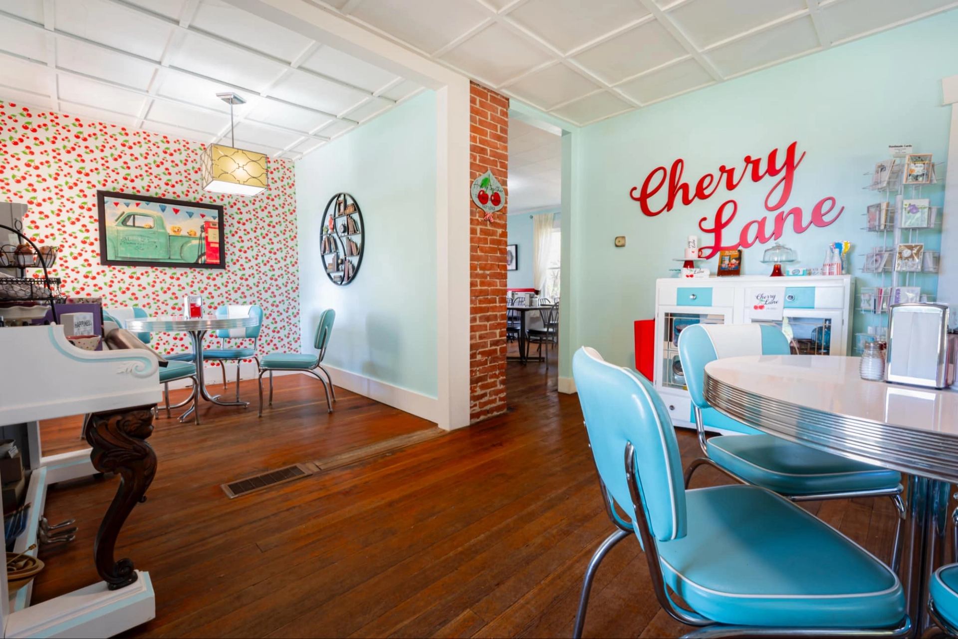 Retro diner-style room with teal chairs, cherry wallpaper and Cherry Lane wall sign