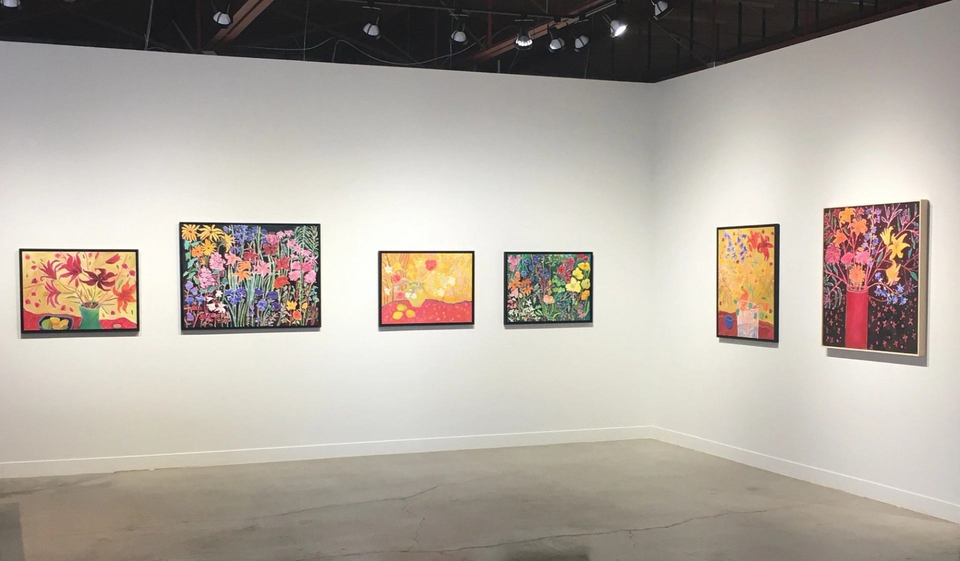 Art gallery wall with framed paintings and spotlights overhead at Peter Robertson Gallery in Edmonto.