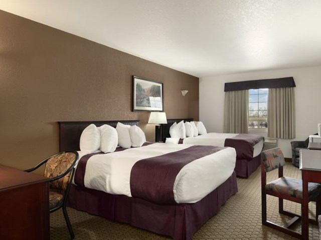Hotel room with two beds, desk, and seating area at Ramada Red Deer.