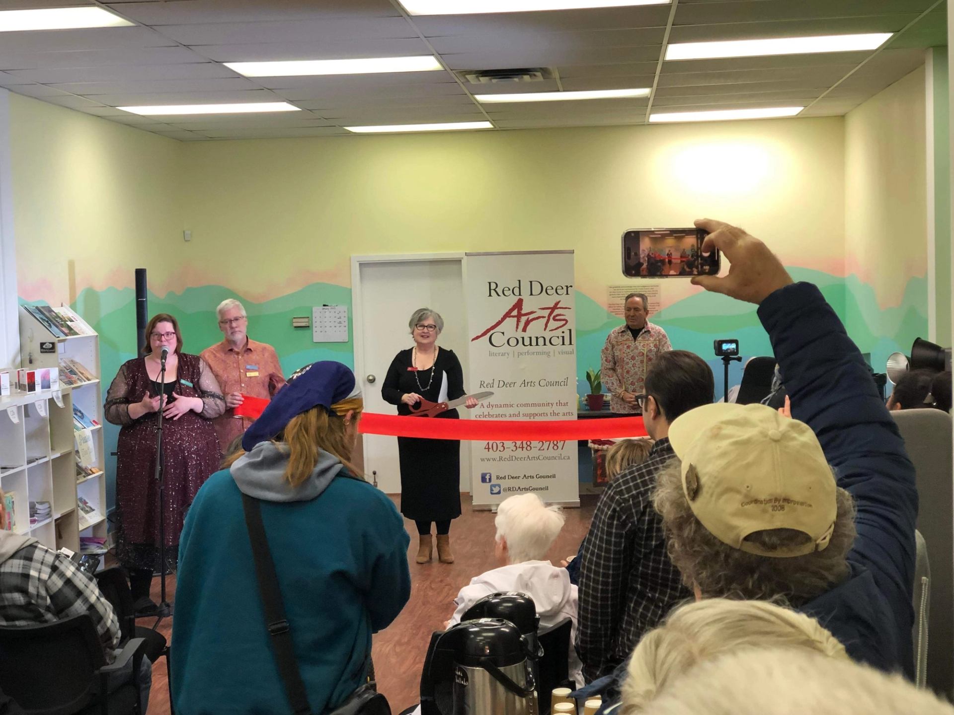Several people in the foreground, watching a ribbon-cutting with an atmospheric landscape behind.