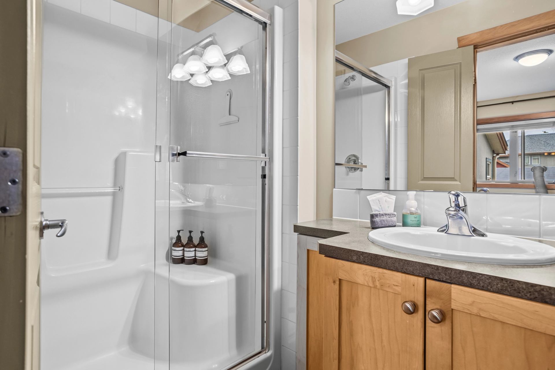 Bathroom with glass-enclosed shower, sink, wooden vanity and large mirror.