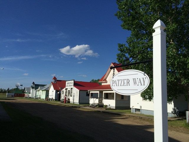 Hanna Pioneer Museum buildings and “Patzer Way” sign beside a road in the Canadian Badlands.