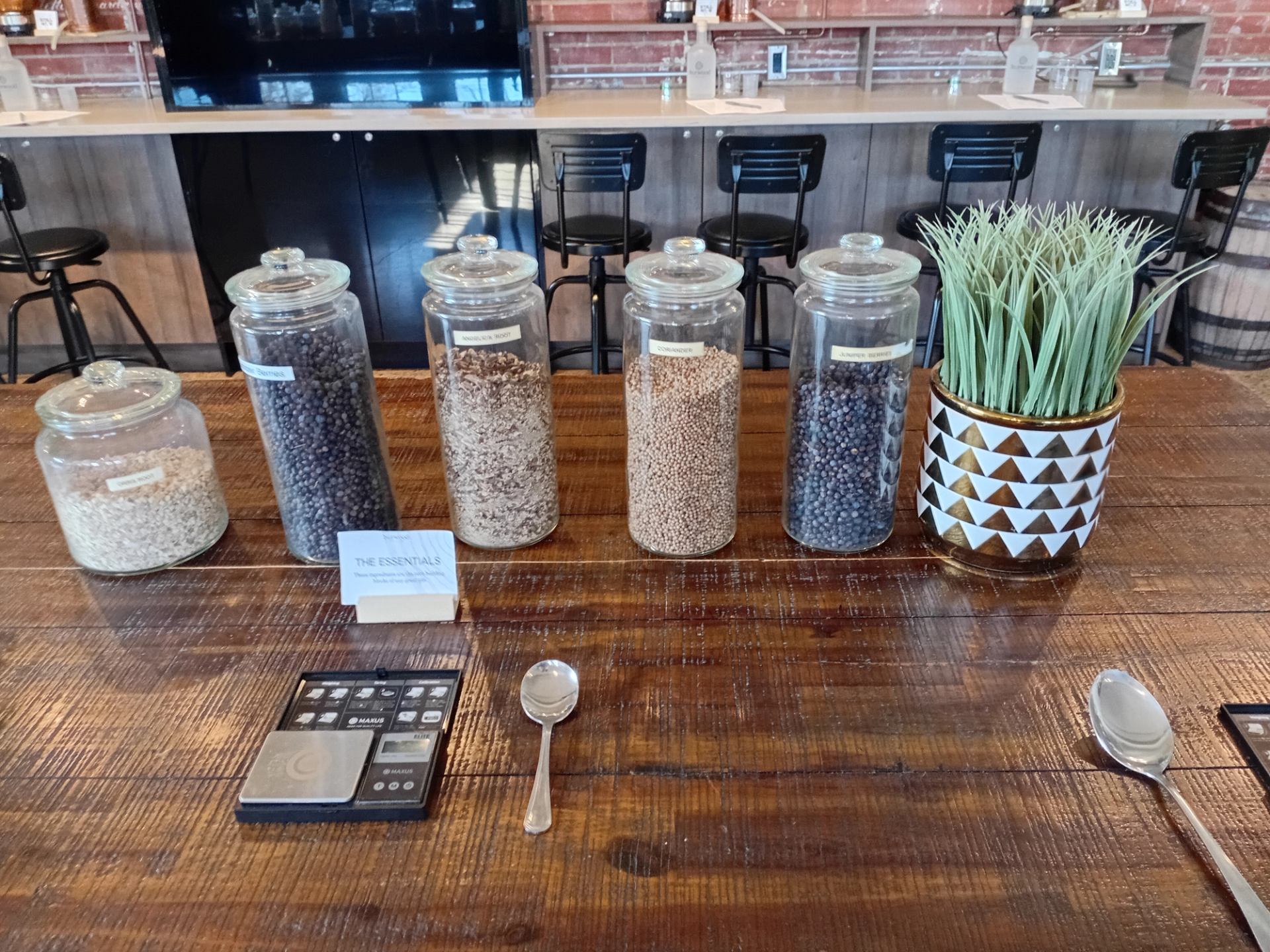 Glass jars of botanicals, spoons and scales sit on a wooden counter.