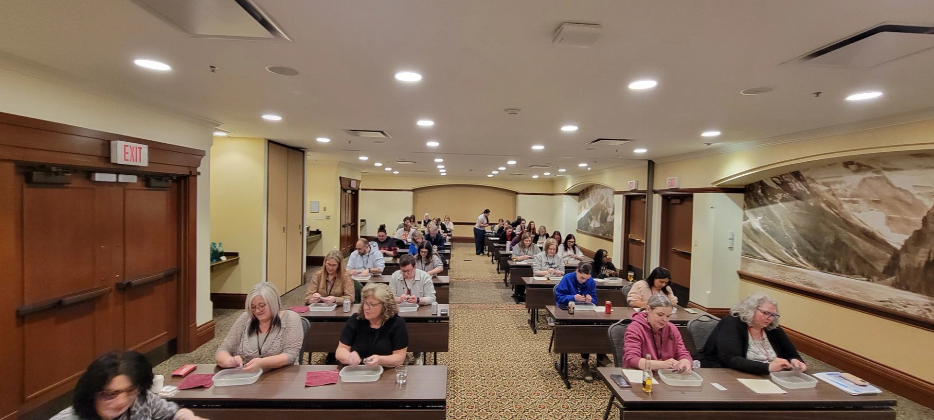 People seated at tables work with containers in a conference room.