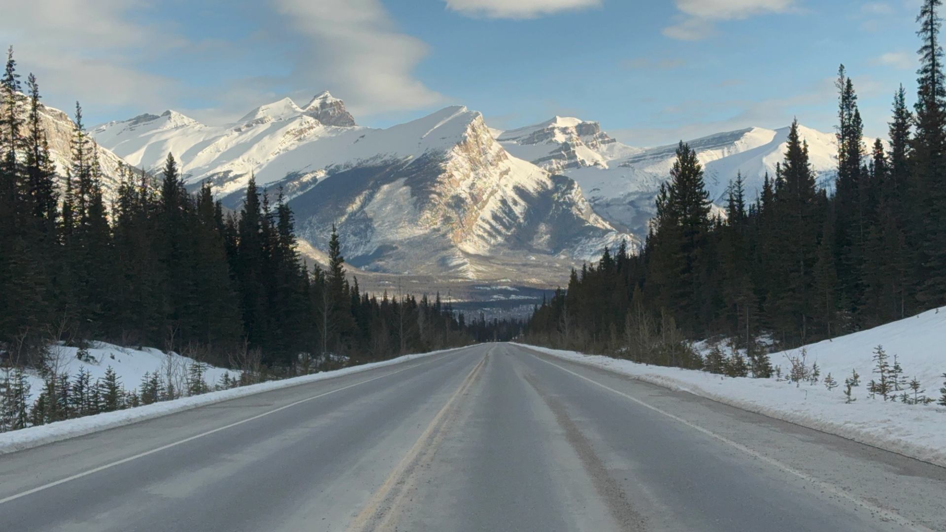 Snowy highway leading to towering Rocky Mountains in Jasper National Park.