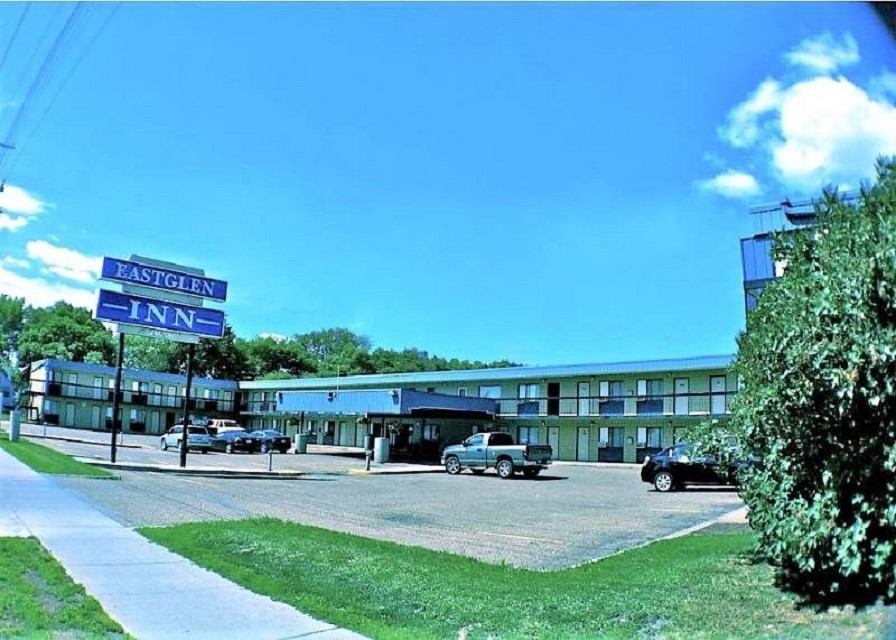 Exterior view of Eastglen Inn with parking lot, sign, and two-story building.