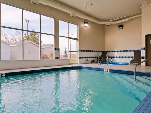 Indoor pool with lounge chairs and large windows at Best Western Plus Red Deer.