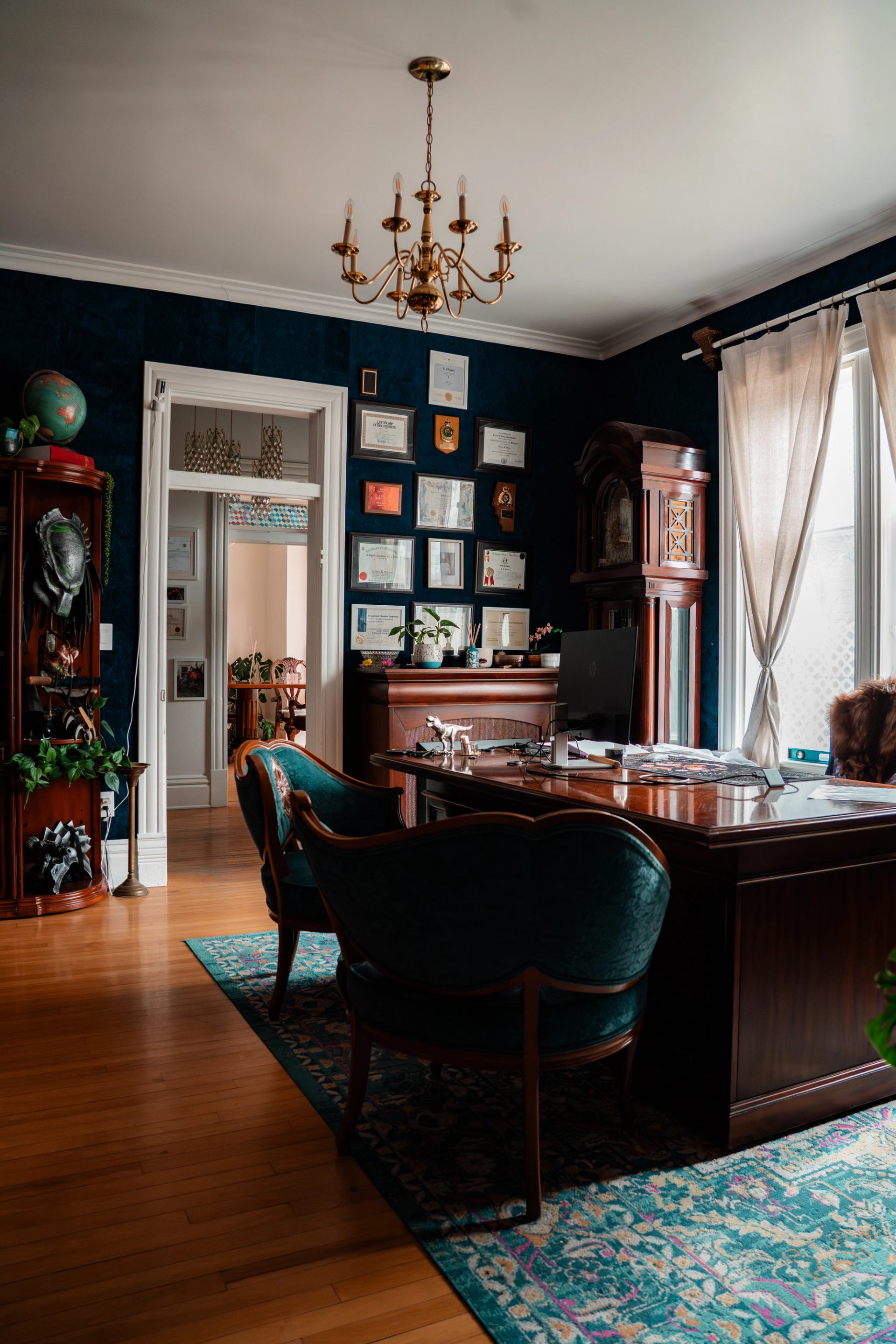 A refined office features antique furnishings, framed awards, and rich décor.