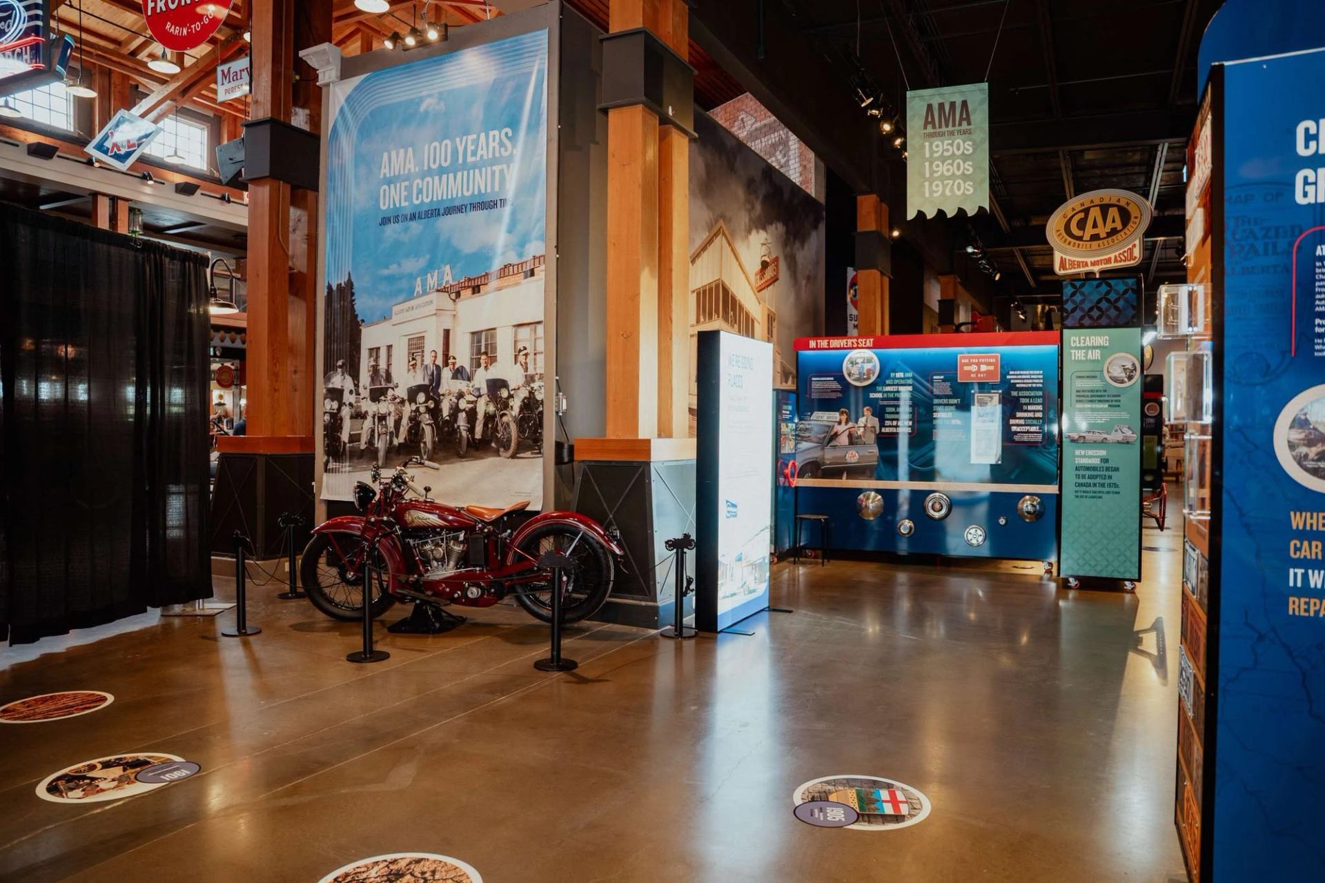 Museum exhibit with vintage motorcycle, AMA history banners and Alberta Motor Association displays.