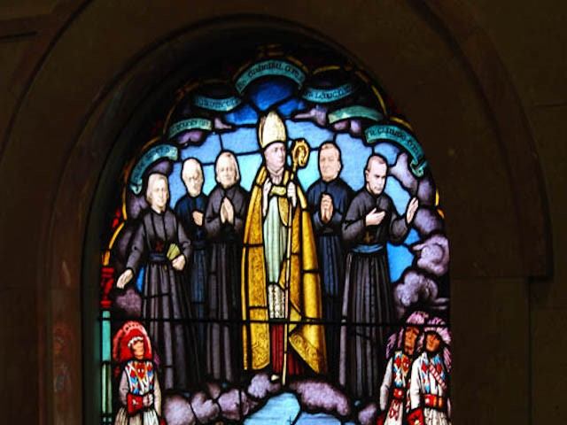 Stained glass showing clergy figures in prayer at St. Mary’s Parish.
