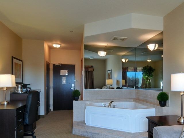 Hotel room at Ramada Drayton Valley with large bathtub, desk, and modern decor.