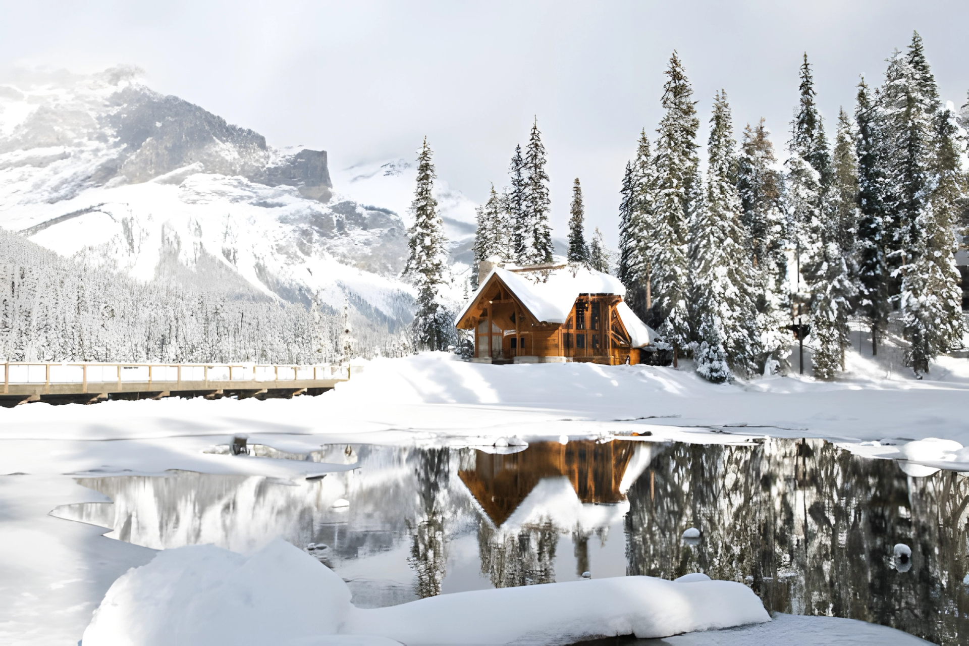 Snowy cabin by a frozen lake with pine trees and mountains in Banff.