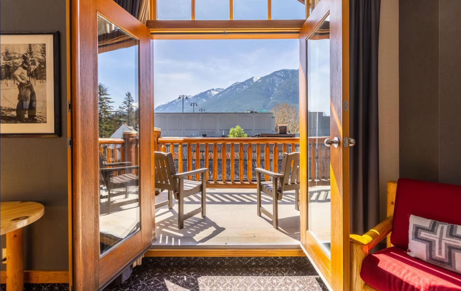 Balcony view with mountain backdrop, outdoor seating, and cozy lodge interior.