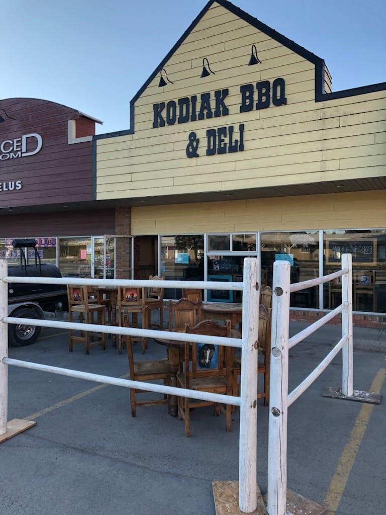 Kodiak BBQ & Deli storefront with outdoor seating and patio chairs behind a white railing.