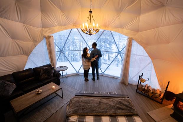 Couple looking out window of Camping Dome at elevated Escapes.