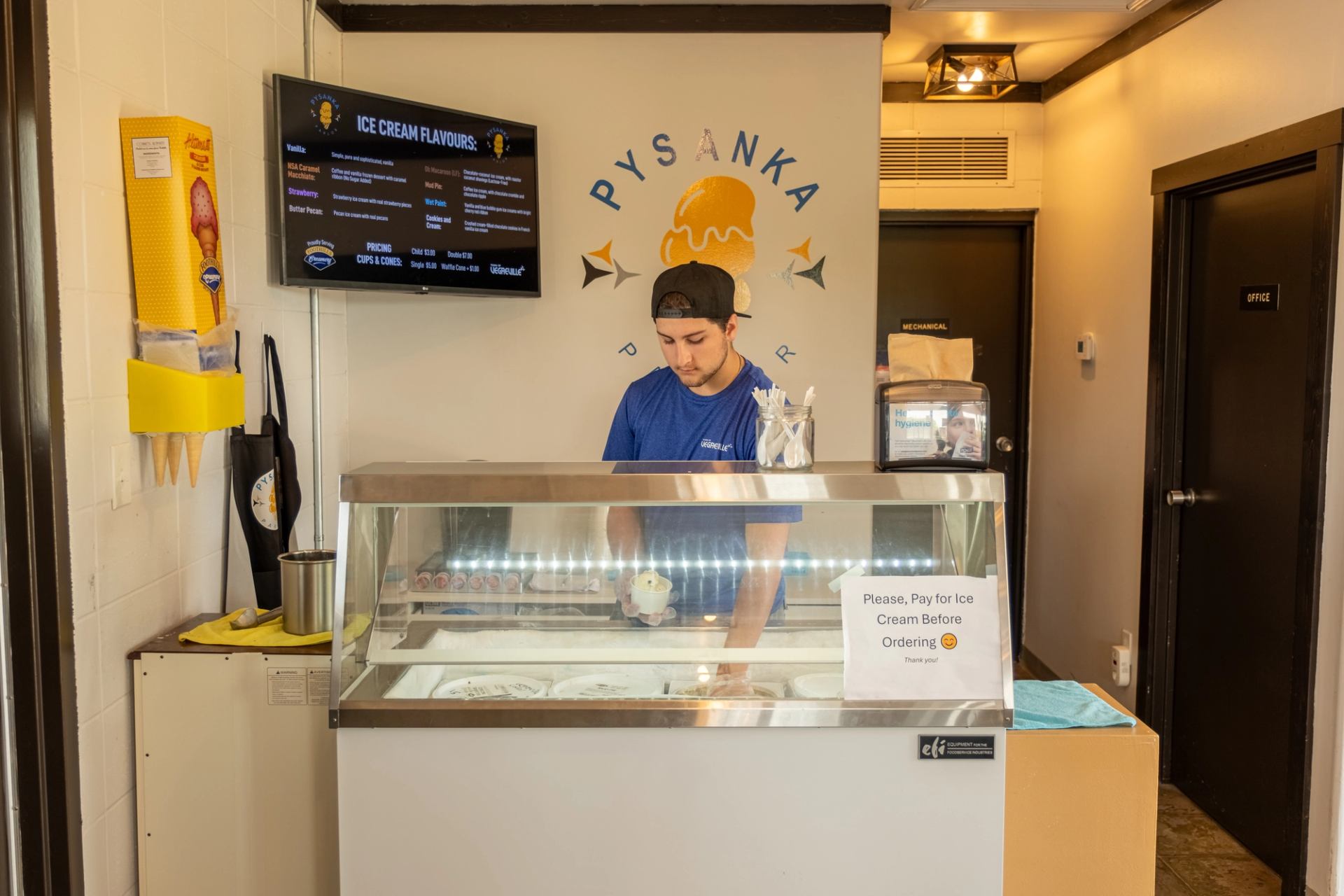  Interior of Pysanka ice cream shop with display case, menu board, and staff.