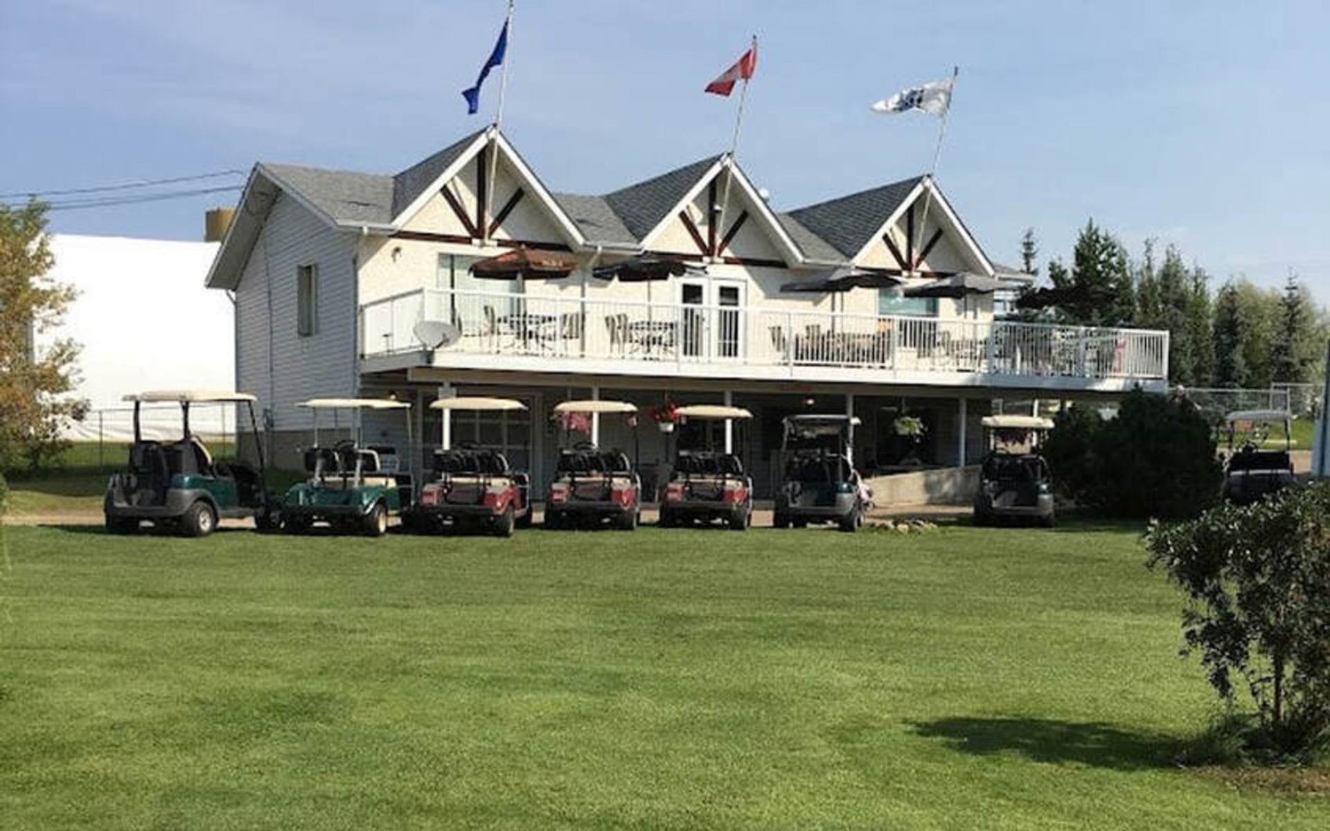 Clubhouse with flags and golf carts parked on the lawn at Paddle River Golf & Country Club.