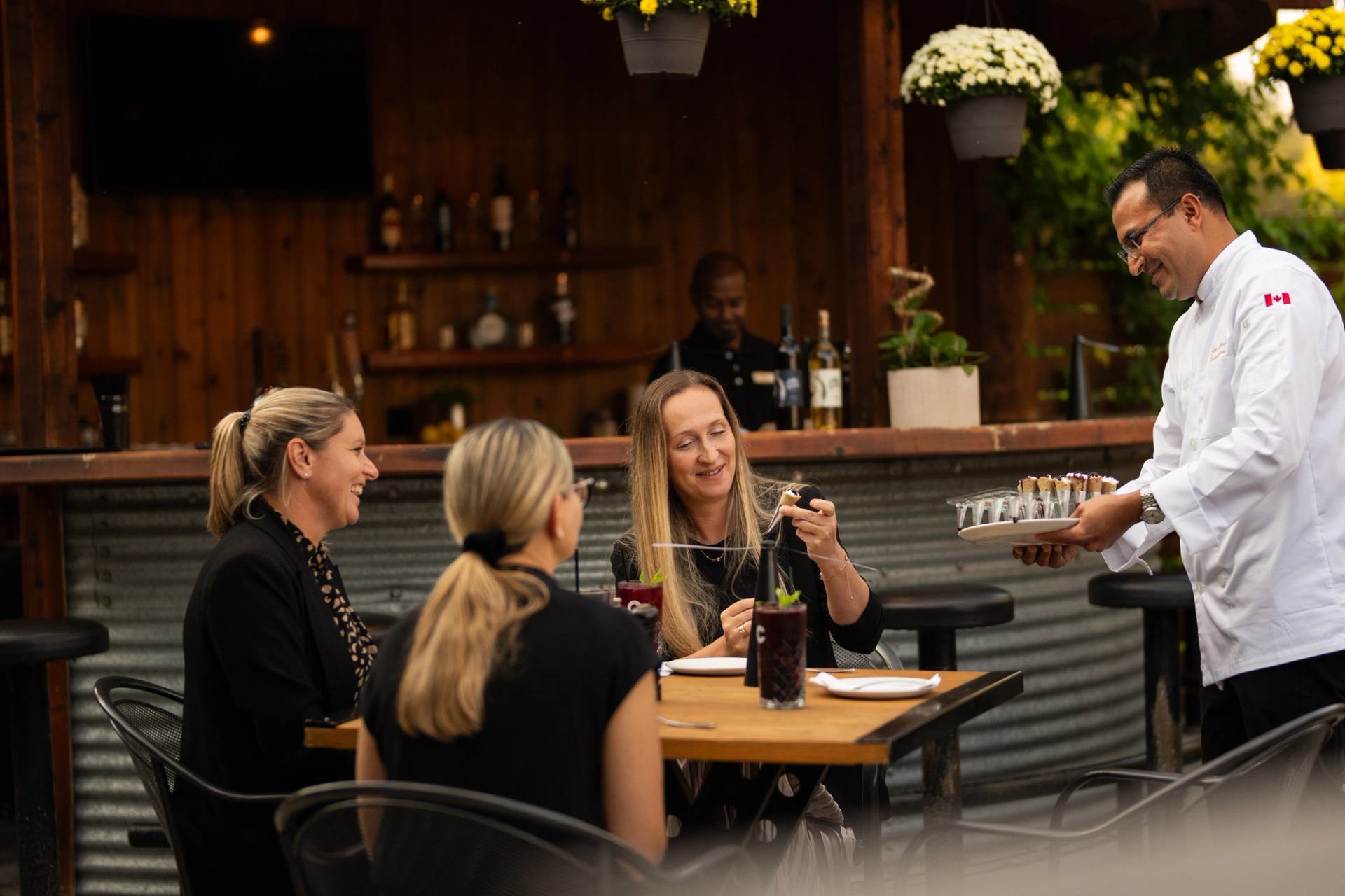 Chef serves drinks to guests at an outdoor dining area at Cattleman’s Chophouse.