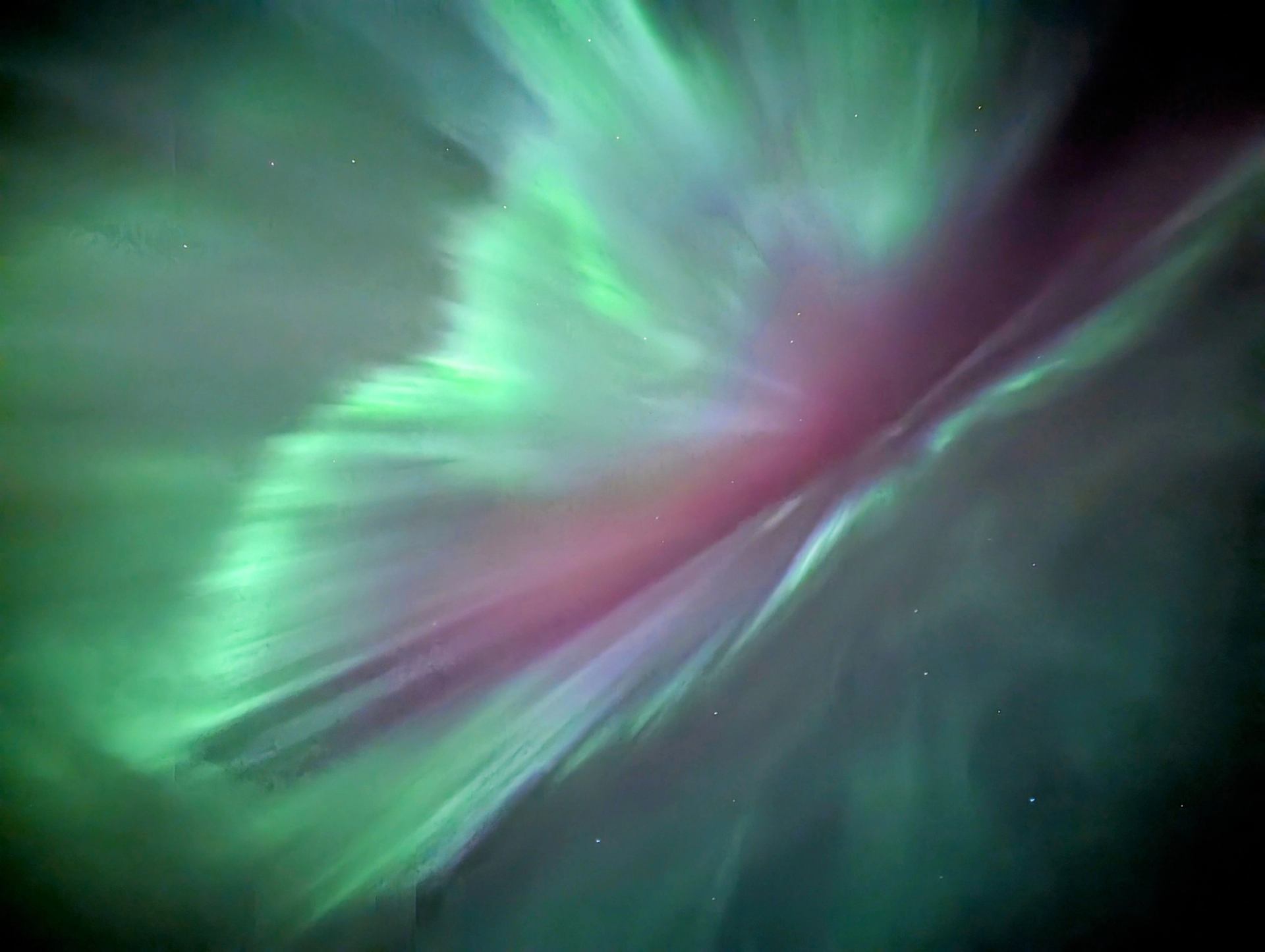 Green and purple aurora lights streaking across the night sky.
