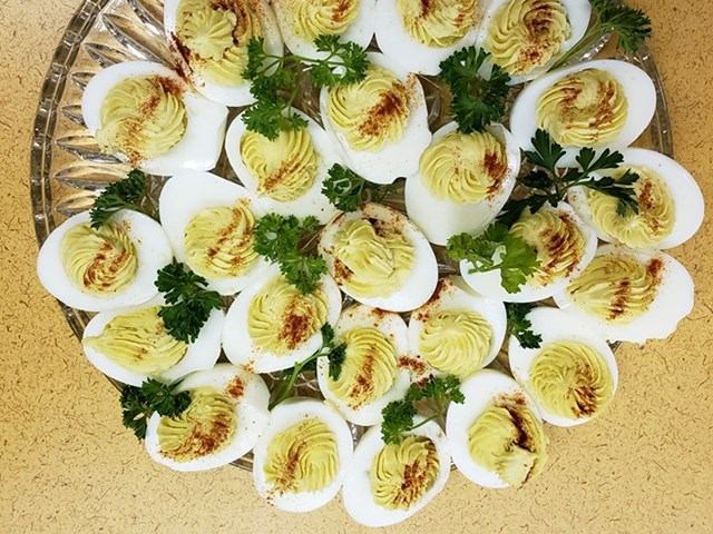 Deviled eggs garnished with paprika and parsley, arranged in a circular pattern.