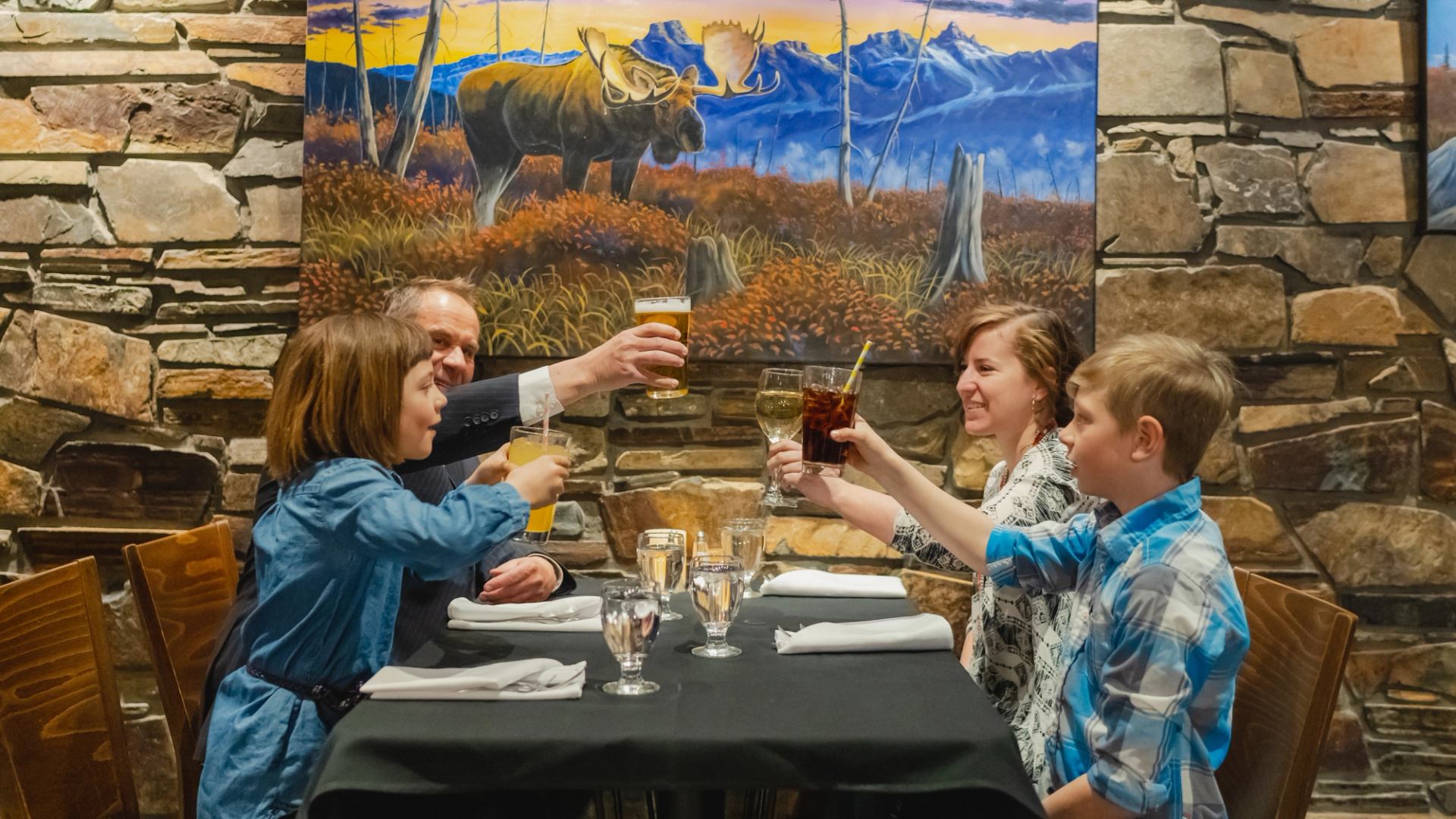 Dining scene with moose painting in background.