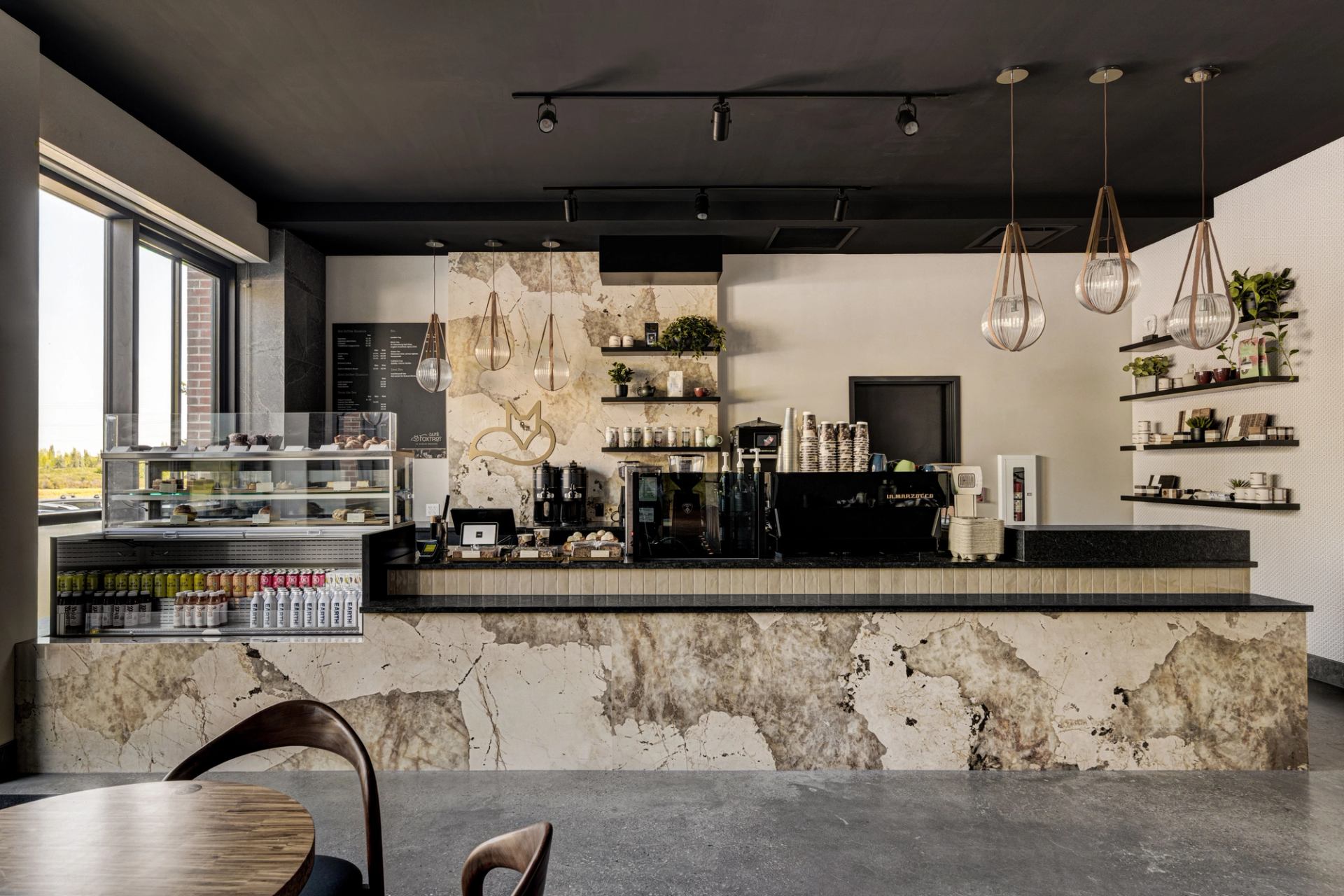 Café Foxtrot counter with espresso machines, marble front, pastry case, and hanging pendant lights.