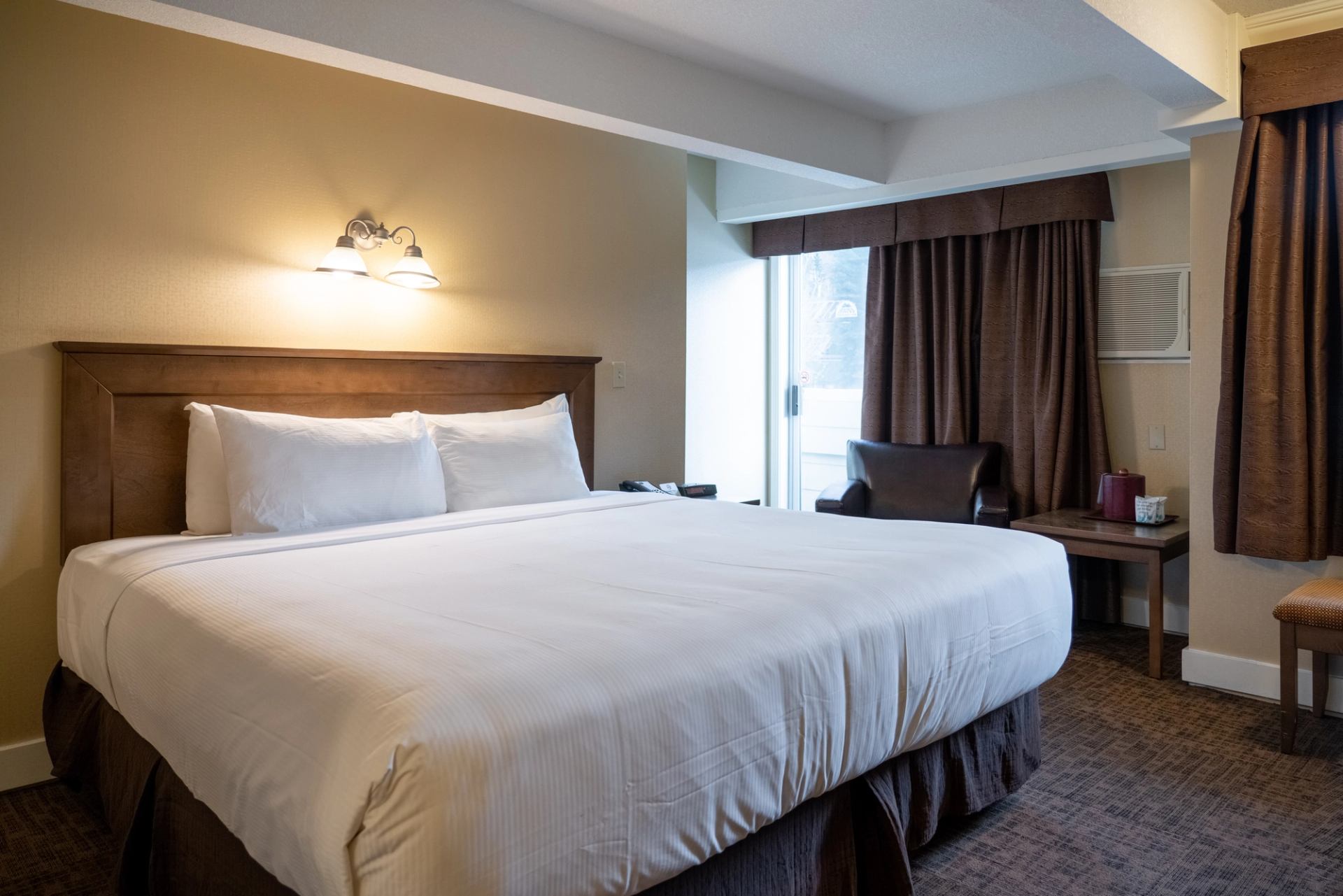 Neat hotel room with large bed, armchair, and soft lighting.