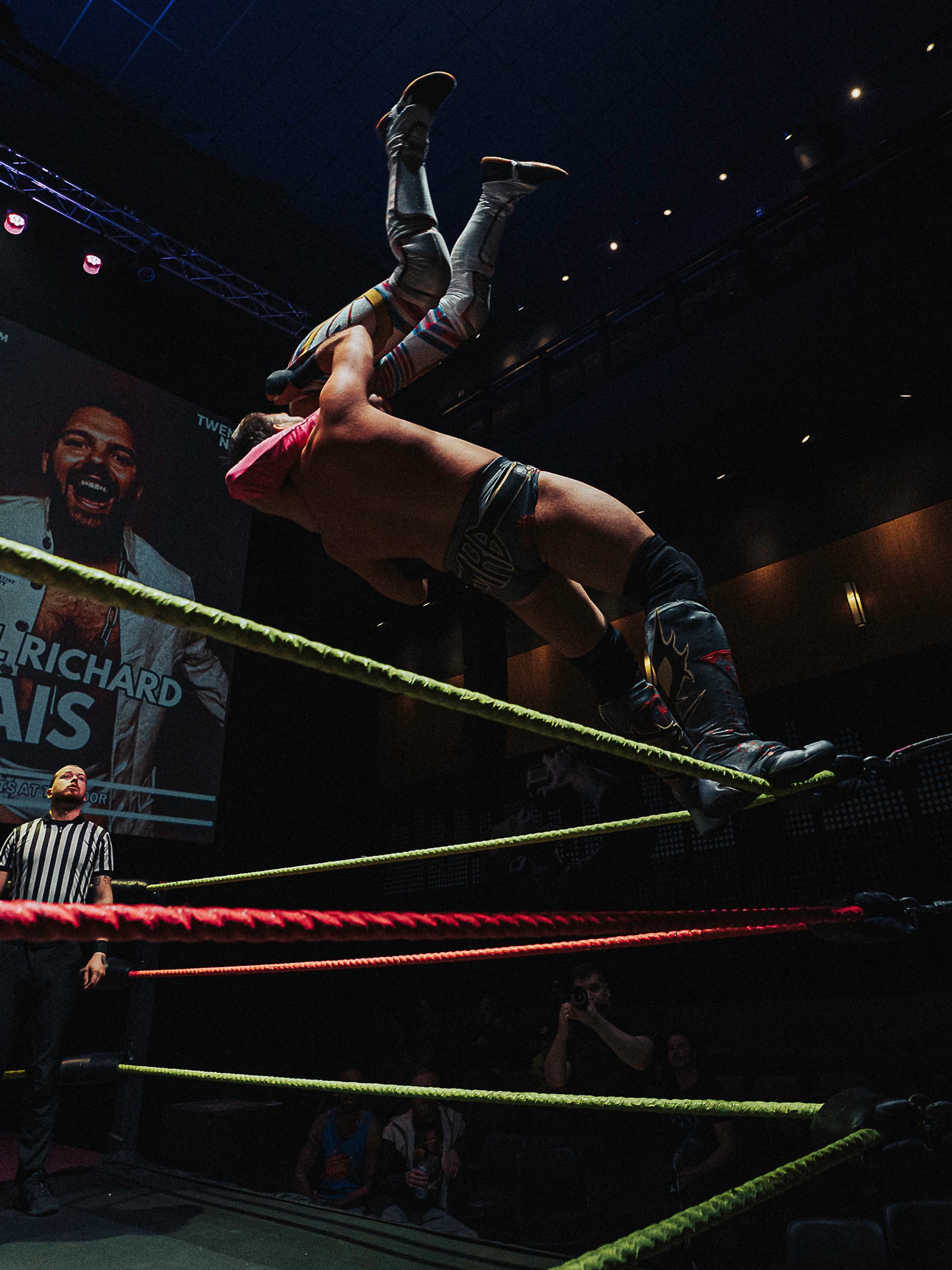 Wrestler performs aerial move in ring during Love Pro Wrestling match.