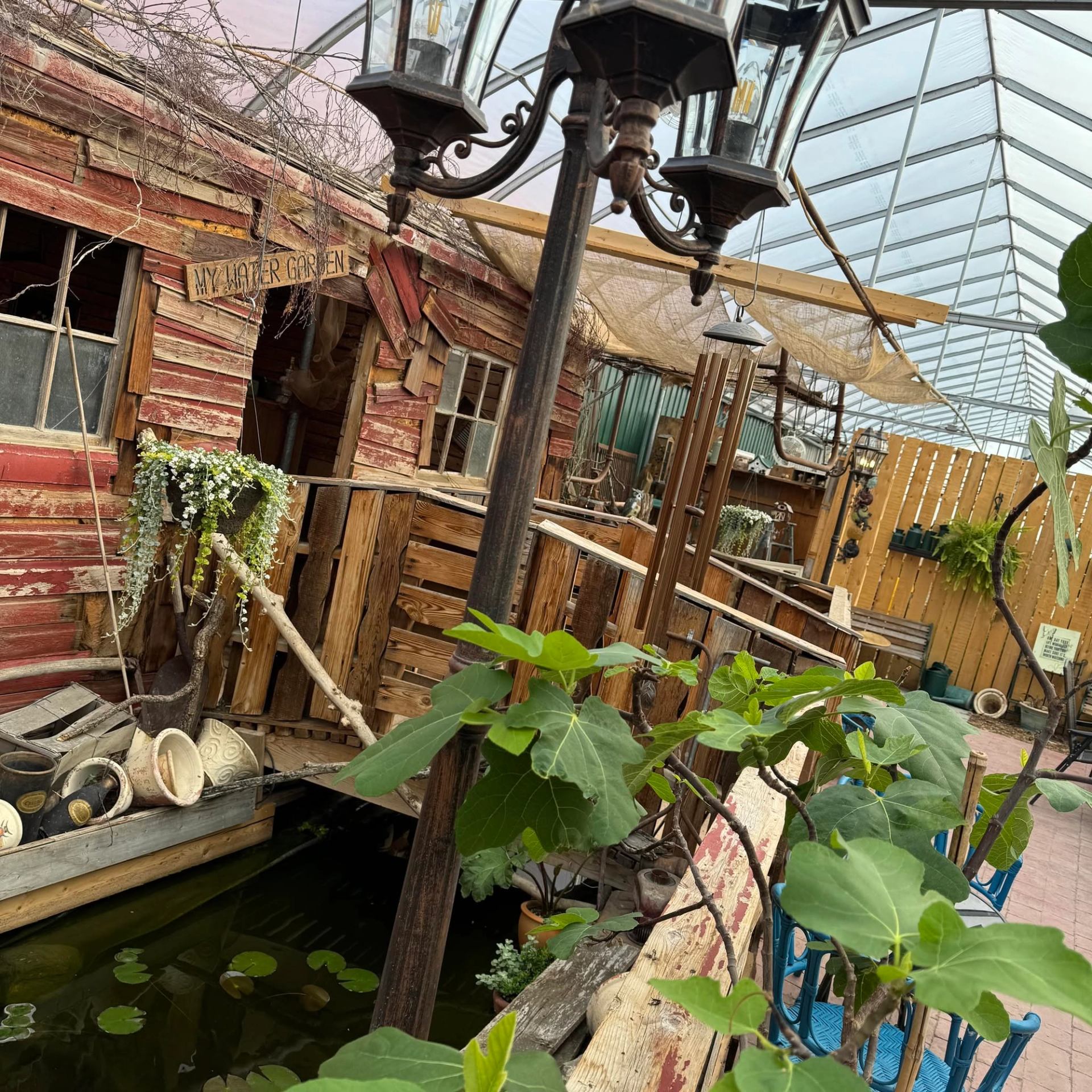The Venue of New Hope features a rustic garden display inside a greenhouse with a pond and plants.