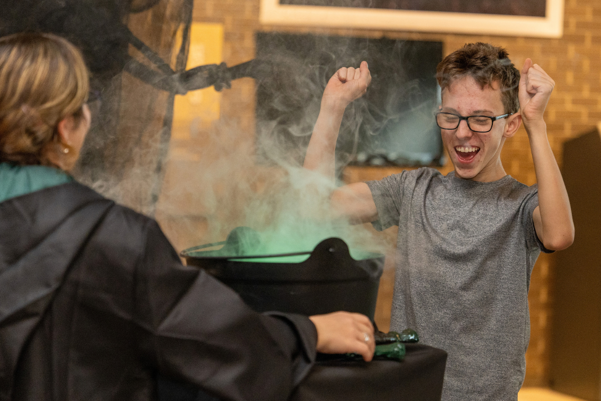 Person raises both arms beside a smoking container as another person looks on.