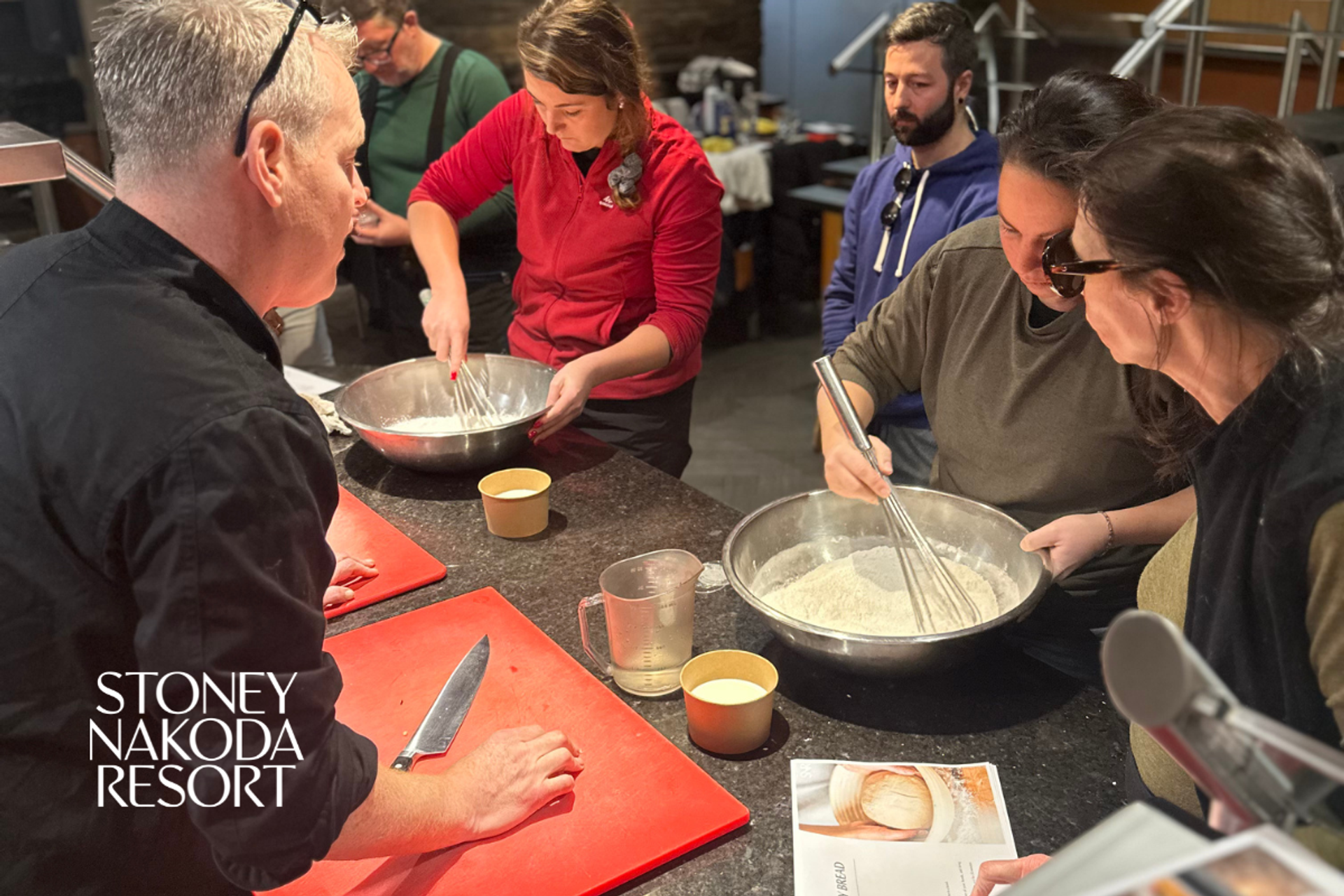  group gathered around mixing bowls during a hands‑on cooking activity at a resort kitchen. 