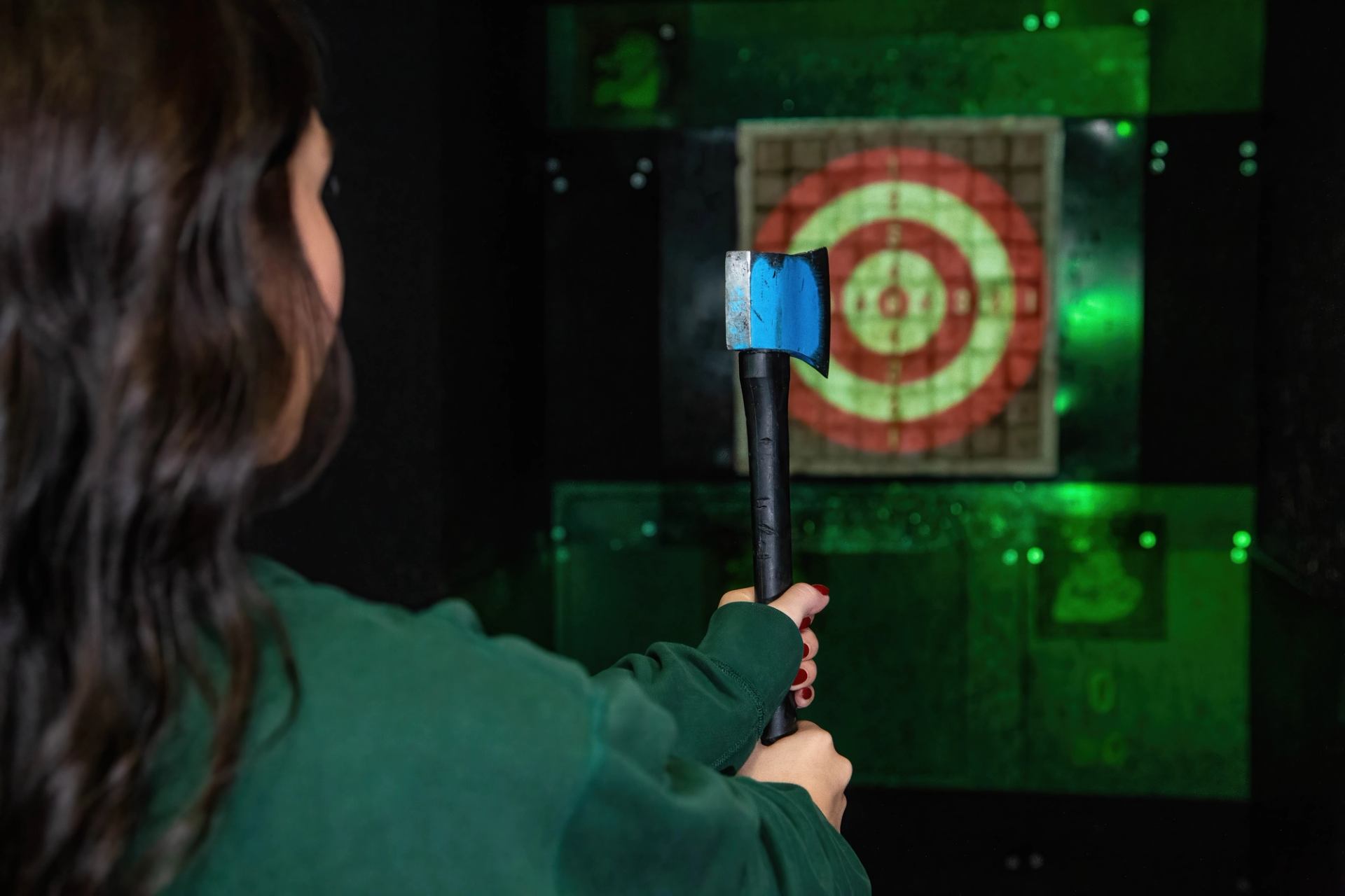 Person holding an axe aimed at a digital target board during an axe-throwing game at Speeders.