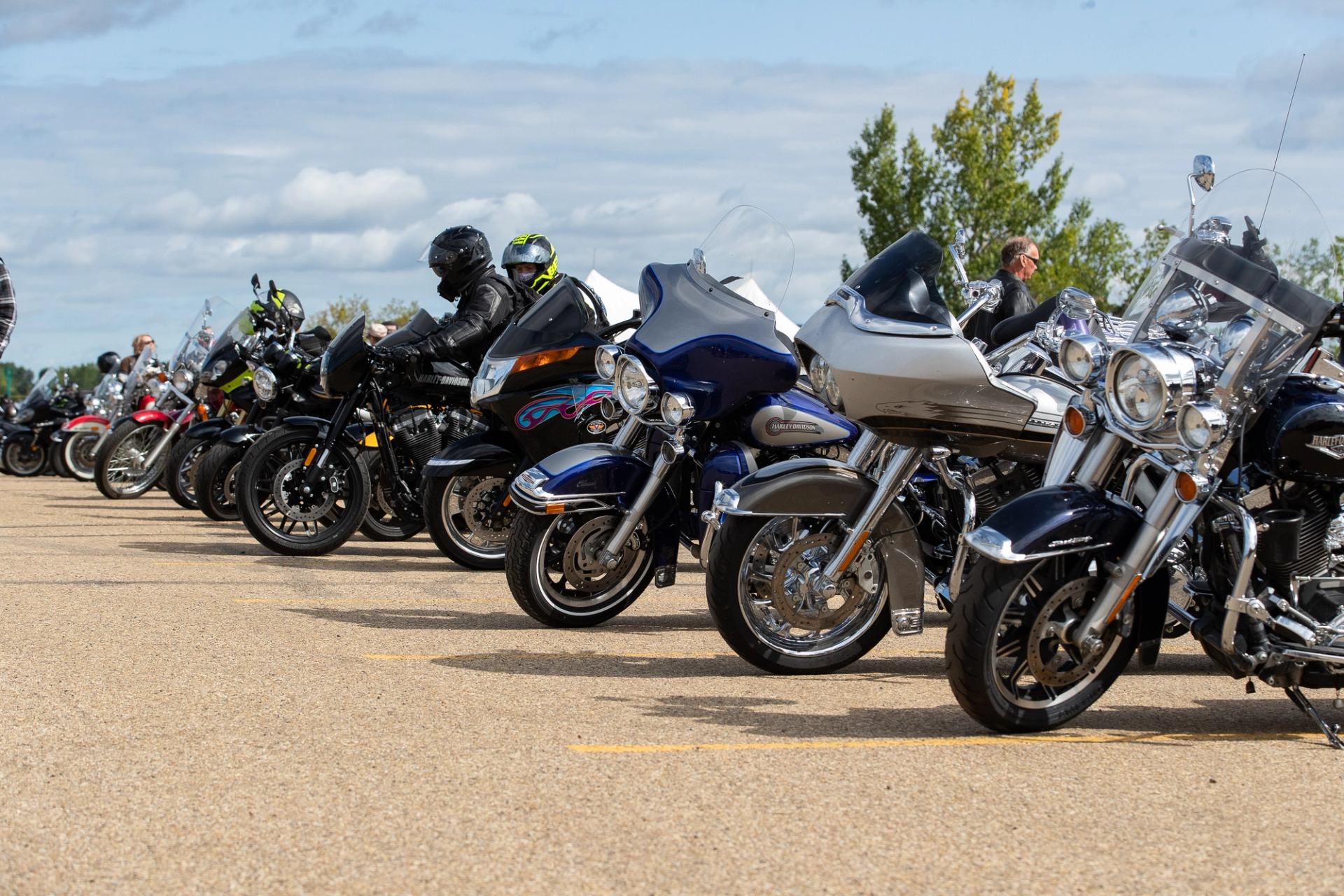 Motorcycles parked in a row with riders getting ready to start the ride.