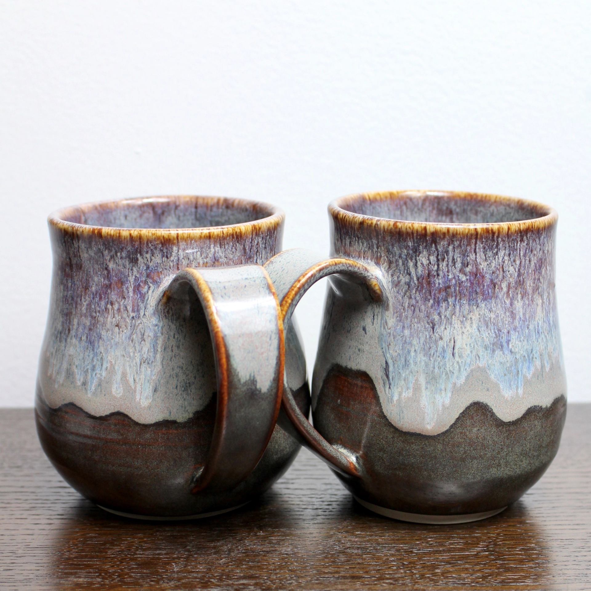 Two pottery mugs on a wooden table.